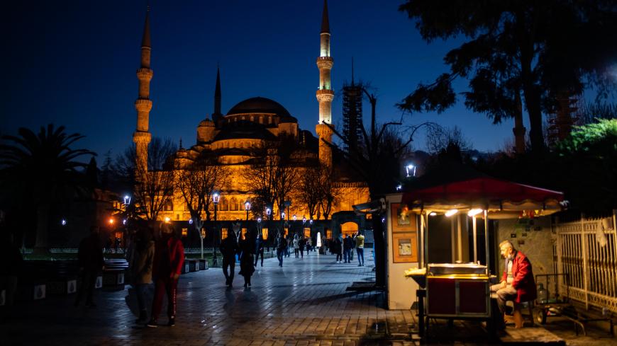 A street vendor sits in front of the Blue Mosque during the new year's celebrations in Istanbul on December 31, 2020. - Turkish government announced a four-days lockdown between December 31 and January 04, 2021. (Photo by Yasin AKGUL / AFP) (Photo by YASIN AKGUL/AFP via Getty Images)