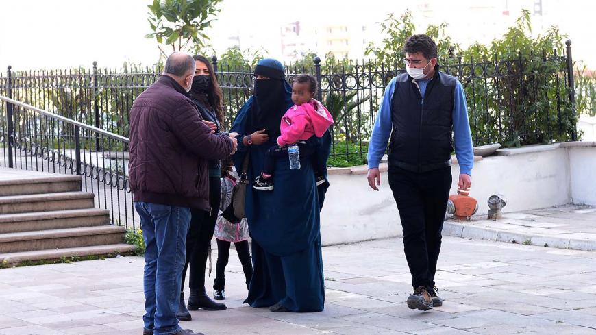 A handout picture taken on February 15, 2021 shows a 26-year-old woman (R), who had held New Zealand and Australian citizenships, and her two children escorted by Turkish plain clothes police officers after trying to enter Turkey illegally from Syria at Reyhanli district in Hatay. - New Zealand Prime Minister Jacinda Ardern angrily accused Australia on February 16, 2021 of shirking its responsibility for a dual national arrested in Turkey with alleged links to the Islamic State militant group. The 40-year-o