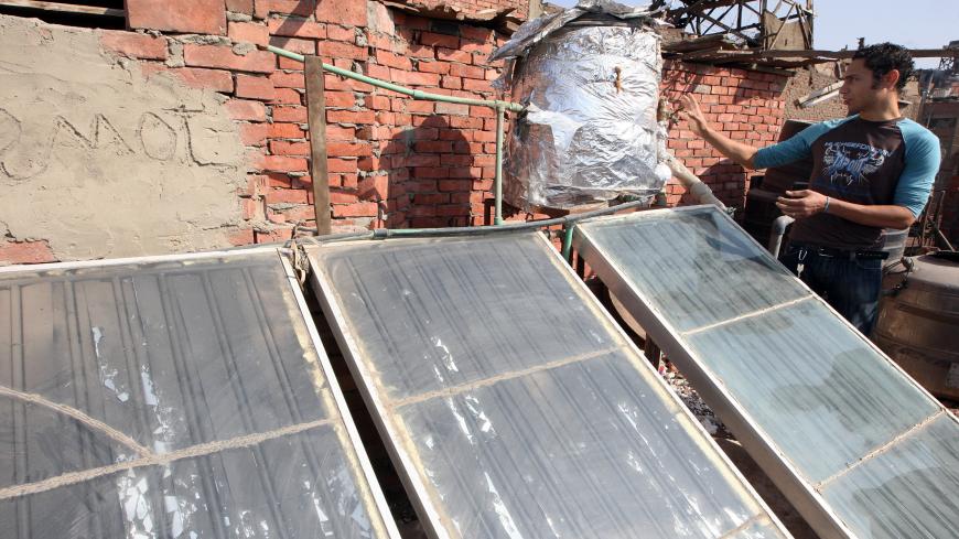 TO GO WITH AFP STORY BY EMMY VARLEY Egyptian Hanna Fathy, an advocate of a biogas project in Egypt, inspects a solar panel installation on his rooftop in Cairo on November 20, 2009. In an attempt to help curb the city's stifling pollution and meet their energy needs too, a few Cairo families have begun to recycle waste -- now that the nation's pigs are gone -- by generating biogas from rubbish. AFP PHOTO/CRIS BOURONCLE (Photo credit should read CRIS BOURONCLE/AFP via Getty Images)