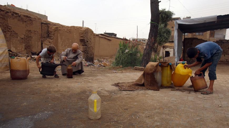 TO GO WITH AFP STORY BY MAHER MOUNNES
A Syrian man and two youths sell locally extracted and refined fuel from a makeshift refinery in Qamishli, a Kurdish-majority city in Hasakeh province, on July 15, 2015. A Kurdish local administration decided to take matters into its own hands, restarting extraction at 150 wells and creating around 20 makeshift refineries producing around 15,000 barrels of oil a day, more than the barely 10,000 bpd that Syria's government generates. AFP PHOTO / YOUSSEF KARWASHAN