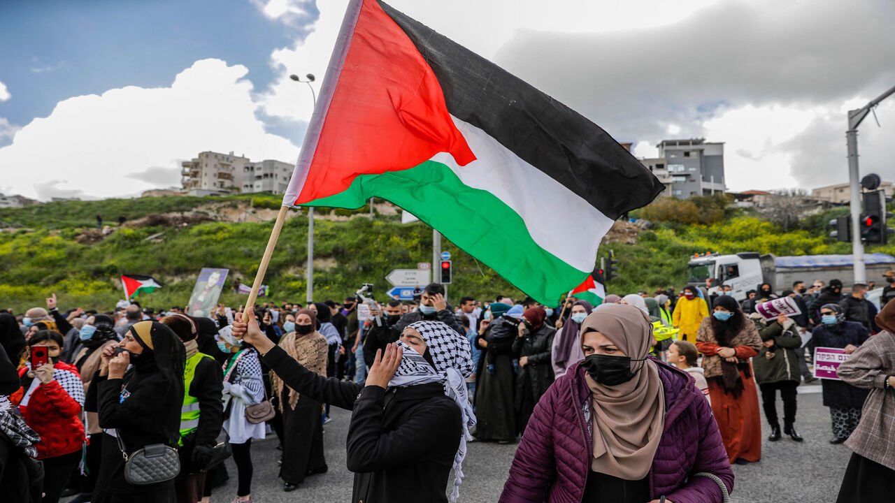 A demonstrator waves a Palestinian flag as Arab Israelis march during a demonstration in the mostly Arab city of Umm al-Fahm, against organized crime and calling upon the Israeli police to stop a wave of intracommunal violence, northern Israel, March 12, 2021.