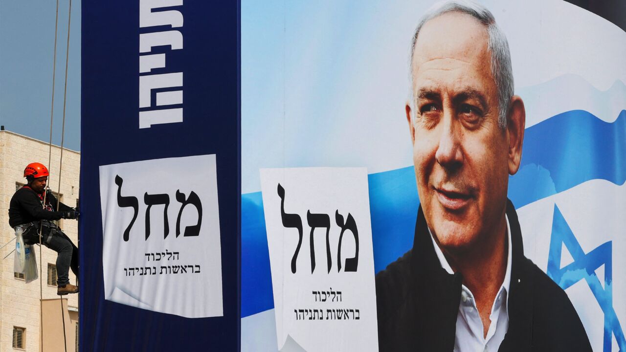 A worker hangs election campaign posters for Israel's Likud party bearing a portrait of its leader Prime Minister Benjamin Netanyahu on a billboard in the Israeli central city of Bnei Brak, on March 14, 2021. - On March 23, the 71-year-old wily politician faces his fourth re-election contest in less than two years, after repeatedly failing to unite a coalition behind him, despite his devoted right-wing base.