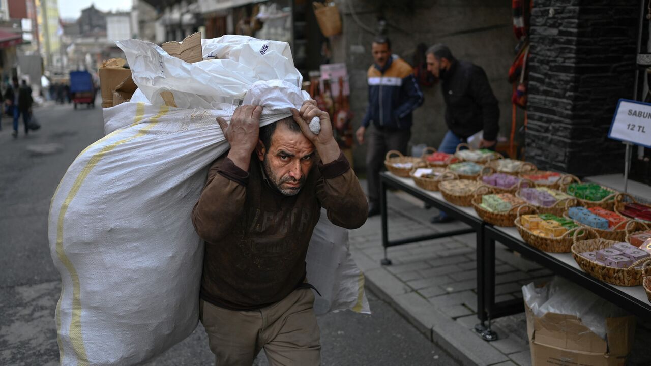 Worker carries sack of goods on back 