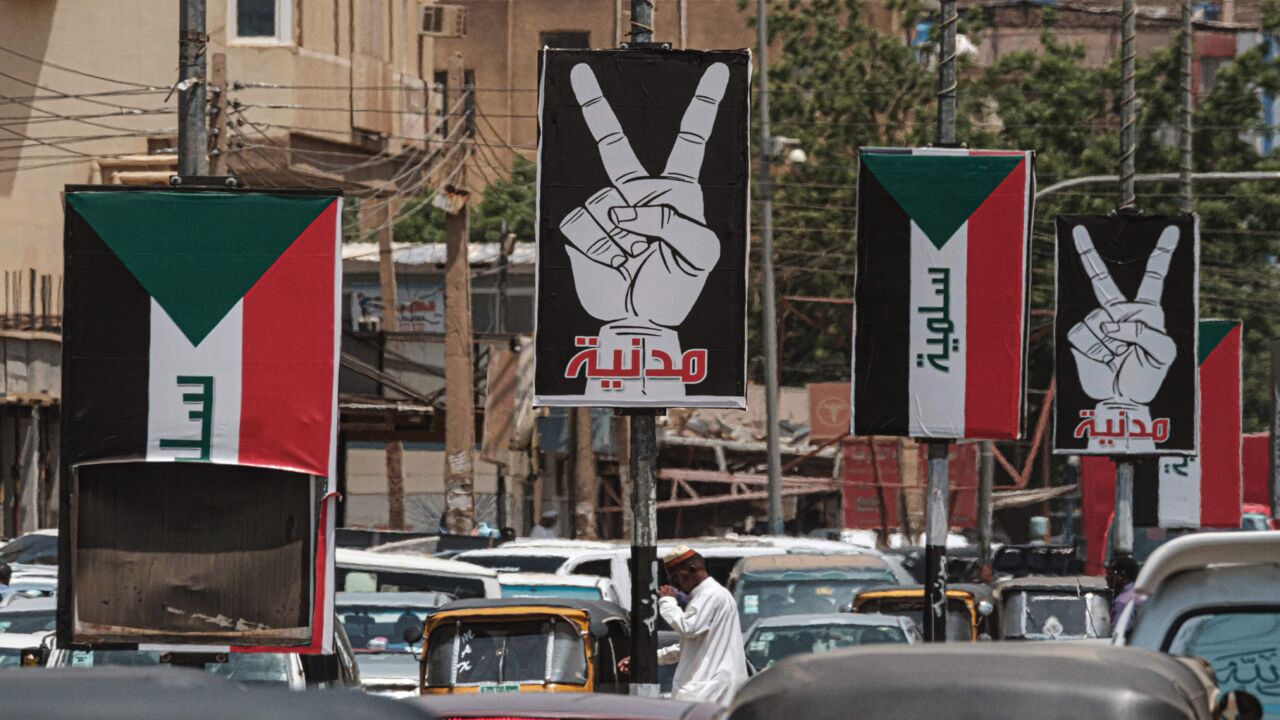 This picture taken on June 15, 2019, shows placards showing the victory gesture with the Arabic word "civilian" and others of the Sudanese flag with the word "peaceful" along a street in the Sudanese capital, Khartoum. 