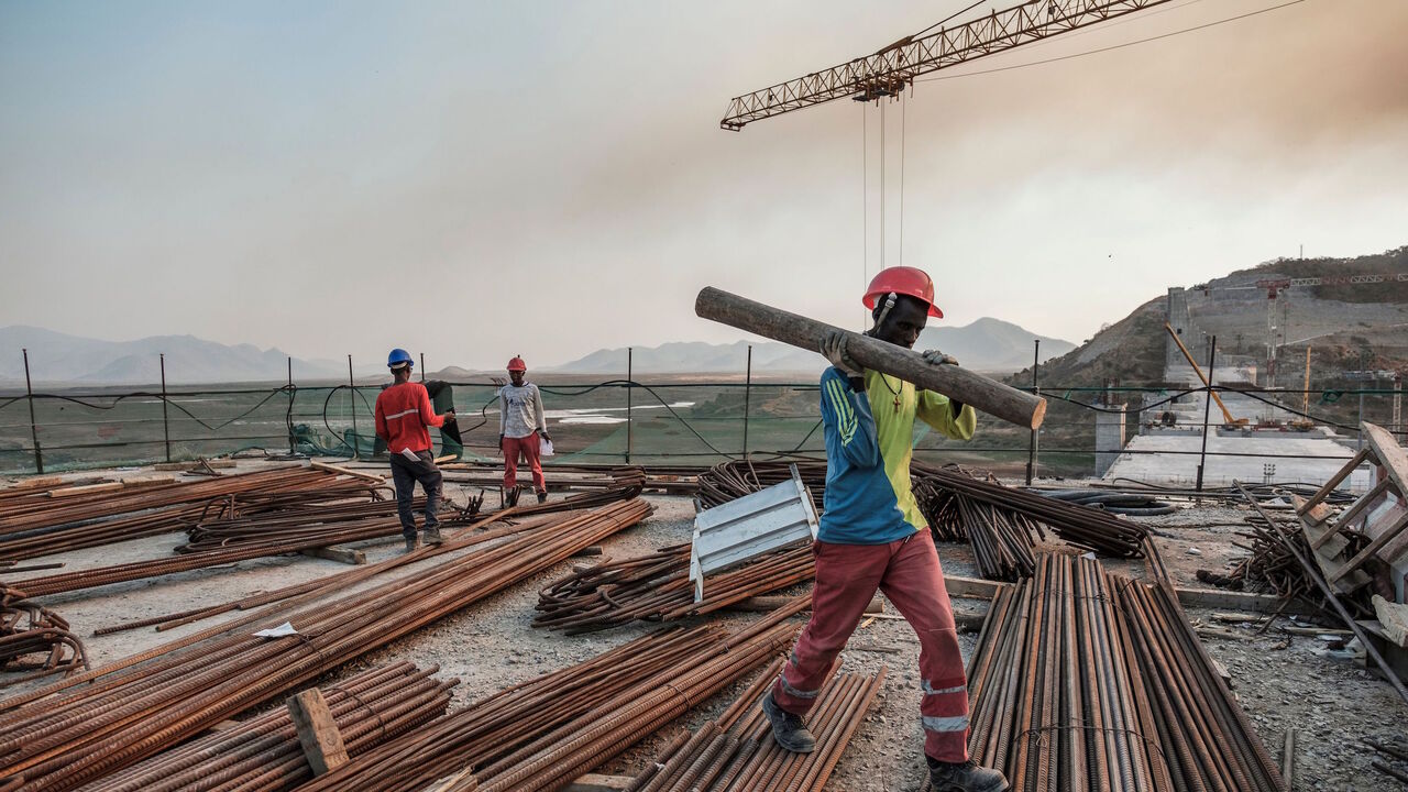 A worker walks with a piece of wood on his shoulder at the Grand Ethiopian Renaissance Dam (GERD), near Guba in Ethiopia, on Dec. 26, 2019.