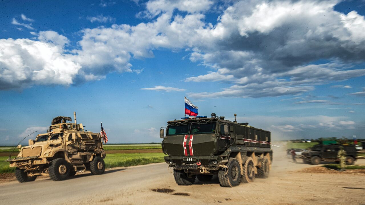 A Russian military police armored truck drives past a US military MRAP (Mine Resistant Ambush Protected) vehicle near the village of Tannuriyah in the countryside east of Qamishli in Syria's northeastern Hasakah province on May 2, 2020.