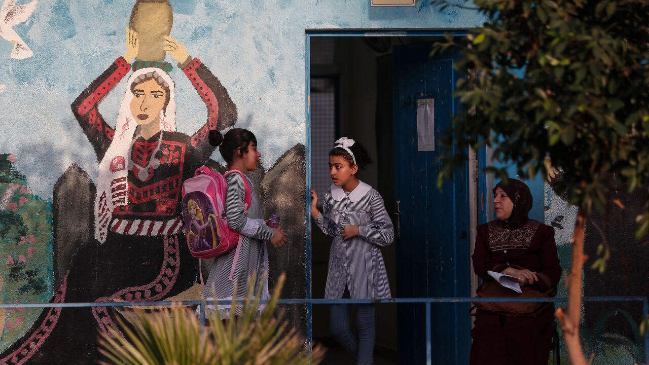 Palestinian students gather in front of a school run by the United Nations Relief and Works Agency (UNRWA) in Jabalia refugee camp in northern Gaza Strip, on the first day of school after local authorities eased some of the restrictions that were imposed in a bid to slow the spread of the novel coronavirus, on Aug. 8, 2020. 