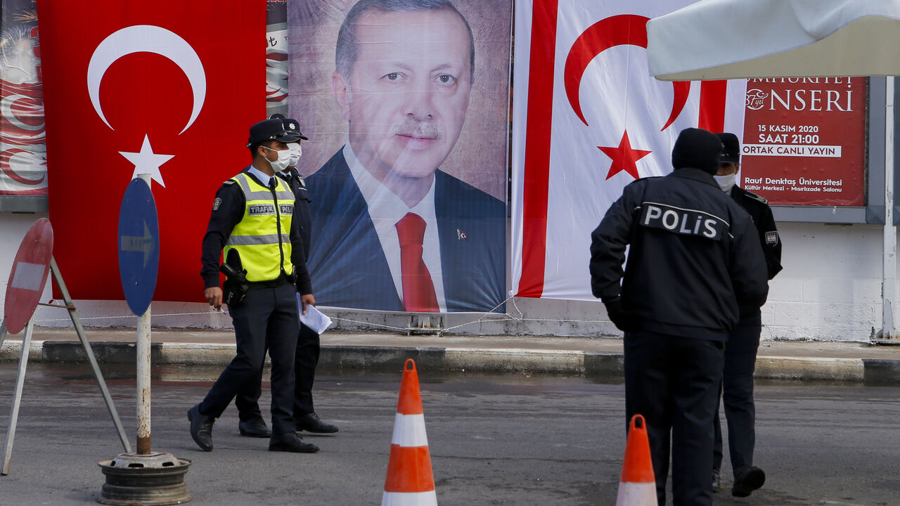 Turkish Cypriot police stand before a portrait of Turkish President Recep Tayyip Erdogan in the disputal coastal town of Varosha, in Famagusta, Cyprus, Nov. 15, 2020.