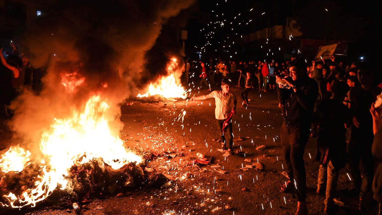 A Palestinian boy plays with a homemade sparkler as tires burn during a rally in support of demonstrators in Jerusalem on April 24, 2021, in Gaza City.