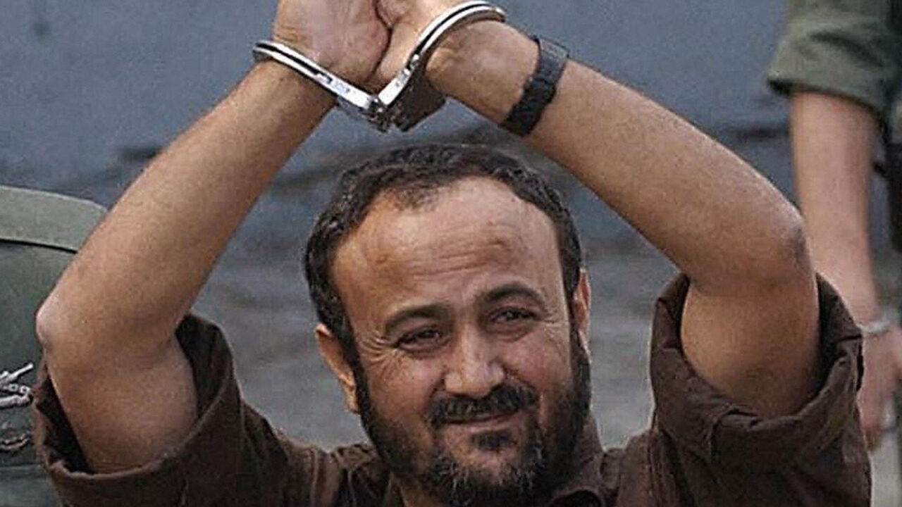 Palestinian West Bank Fatah leader Marwan Barghuti flanked by Israeli guards walks into a Tel Aviv court 20 May 2004.