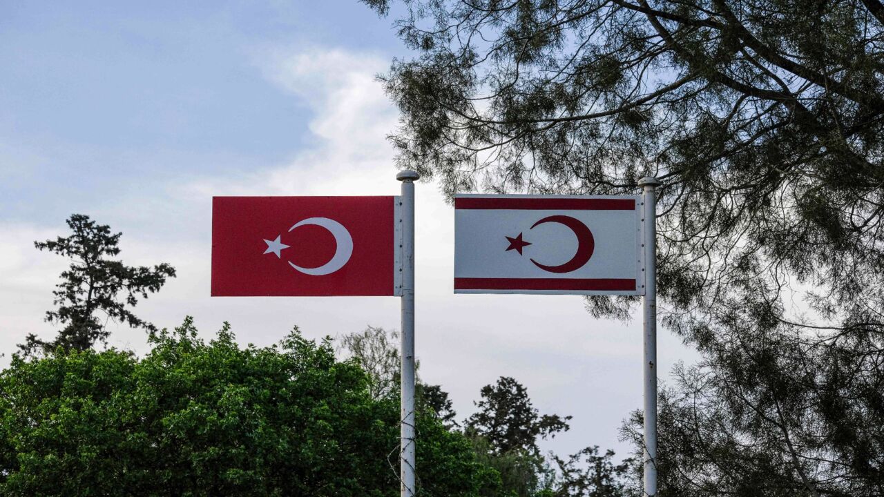 A picture taken from the Greek-Cypriot side of the divided Cypriot capital Nicosia on April 24, 2021, shows metal flags of Turkey (L) and the self-declared Turkish Republic of North Cyprus (TRNC), recognized only by Ankara, above the Turkish-controlled side of the divided capital.