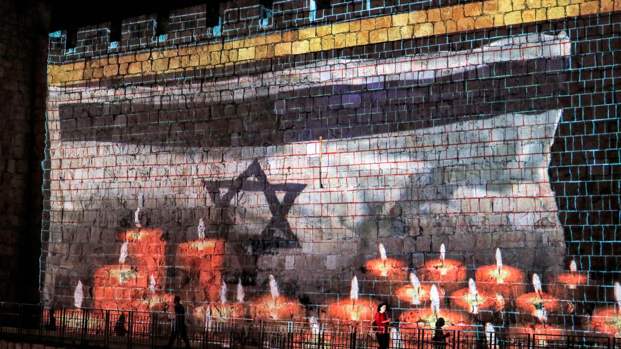 A projection of an Israeli flag flying before lit candles is displayed on the Old City walls of Jerusalem, as Israel declares a national day of mourning for victims of a stampede during the Lag Ba'Omer holiday at Mount Meron, May 2, 2021,