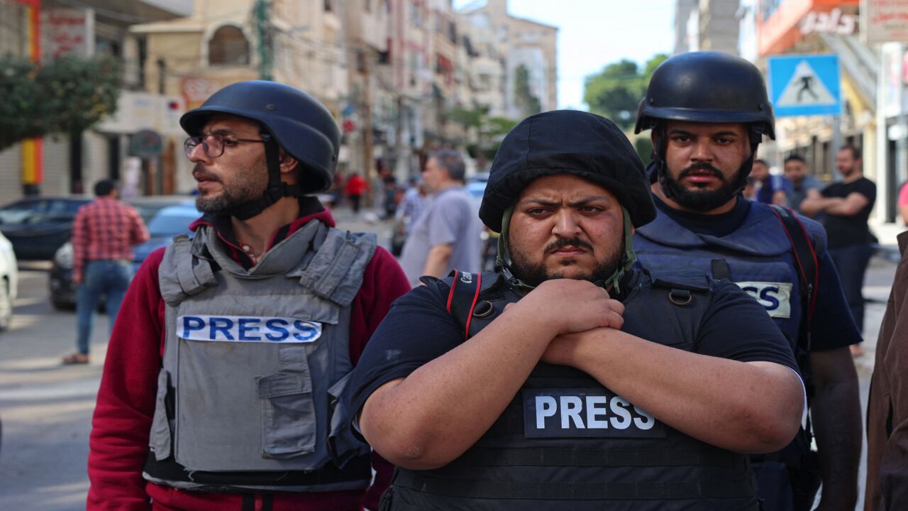 Palestinian journalists stand in shock following the destruction of Jala Tower, which was housing international press offices, by an Israeli airstrike in the Gaza Strip on May 15, 2021. The Israeli airstrike demolished the 13-floor building housing Qatar-based Al Jazeera television and American news agency The Associated Press in the Gaza Strip. 