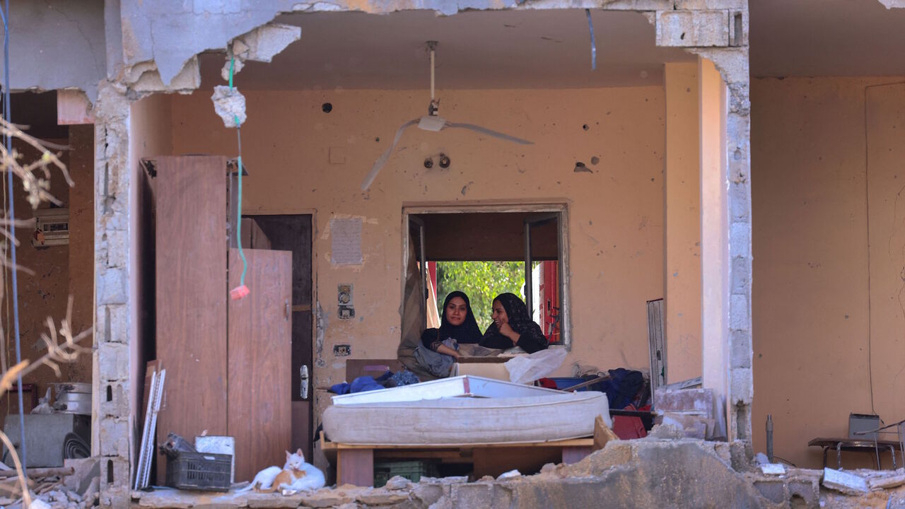 Palestinian women sit in the rubble of a building, destroyed by Israeli strikes, in Beit Hanun in the northern Gaza Strip on May 21, 2021. 