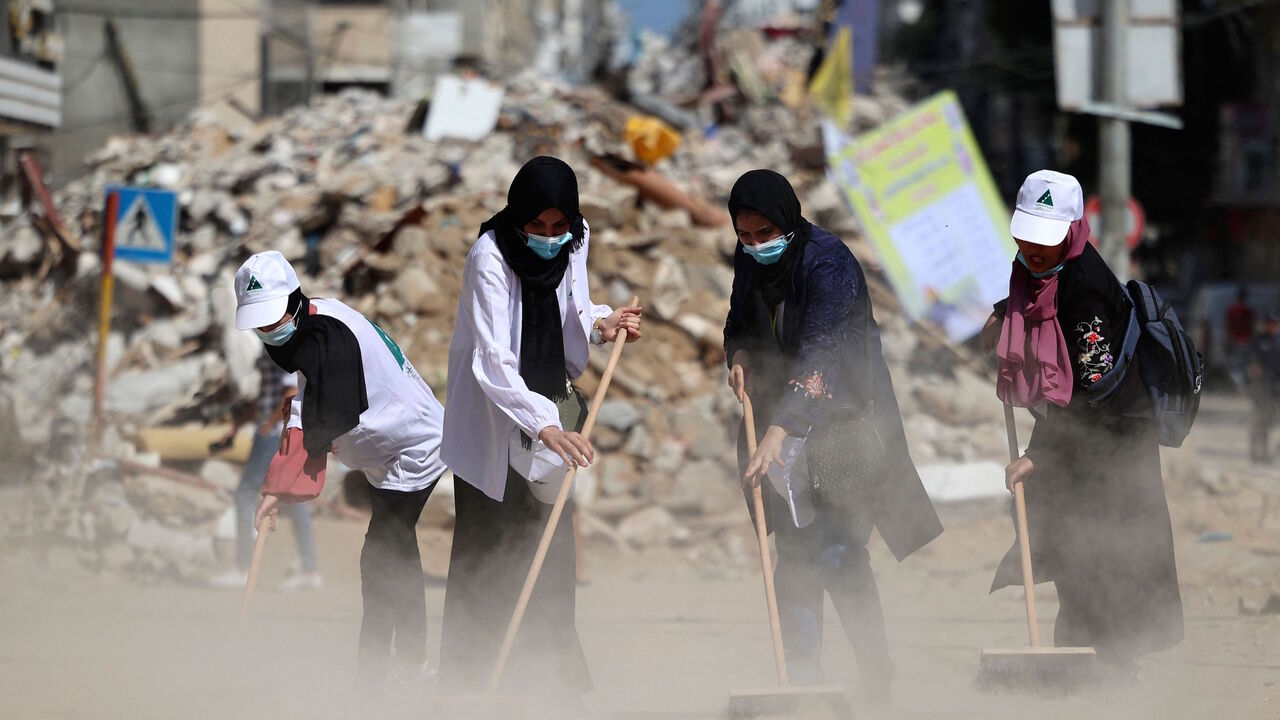 Palestinian volunteers sweep the rubble of buildings, recently destroyed by Israeli strikes, in Gaza City's Rimal district on May 25, 2021. 