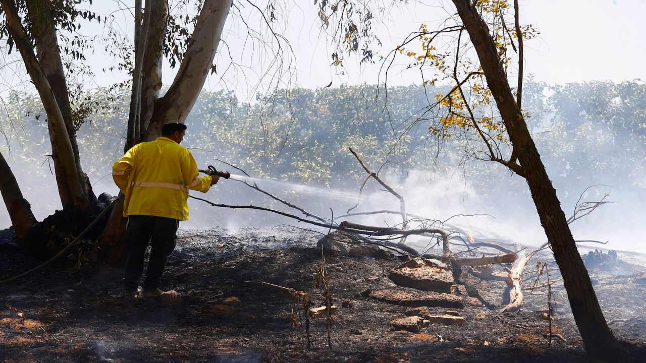 A worker with the Israel Nature and Parks Authority extinguishes a fire in a field near Kibutz Alumim that was reportedly caused by an incendiary balloon launched from the Gaza Strip, Aug. 24, 2020. 