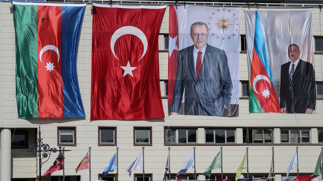 The national flags of Azerbaijan (L) and Turkey, and portraits of Turkish President Recep Tayyip Erdogan and Azerbaijani President Ilham Aliyev (R) hang side-by-side on the mayoral building in the Kecioren district of Ankara on October 21, 2020.  