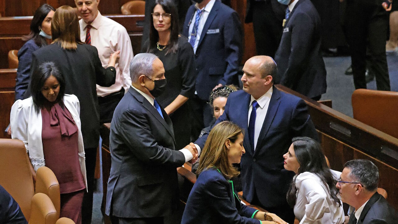 (L to R) Israel's outgoing prime minister Benjamin Netanyahu shakes hands with his successor, incoming Prime Minister Naftali Bennett, after a special session to vote on a new government at the Knesset in Jerusalem, on June 13, 2021. 