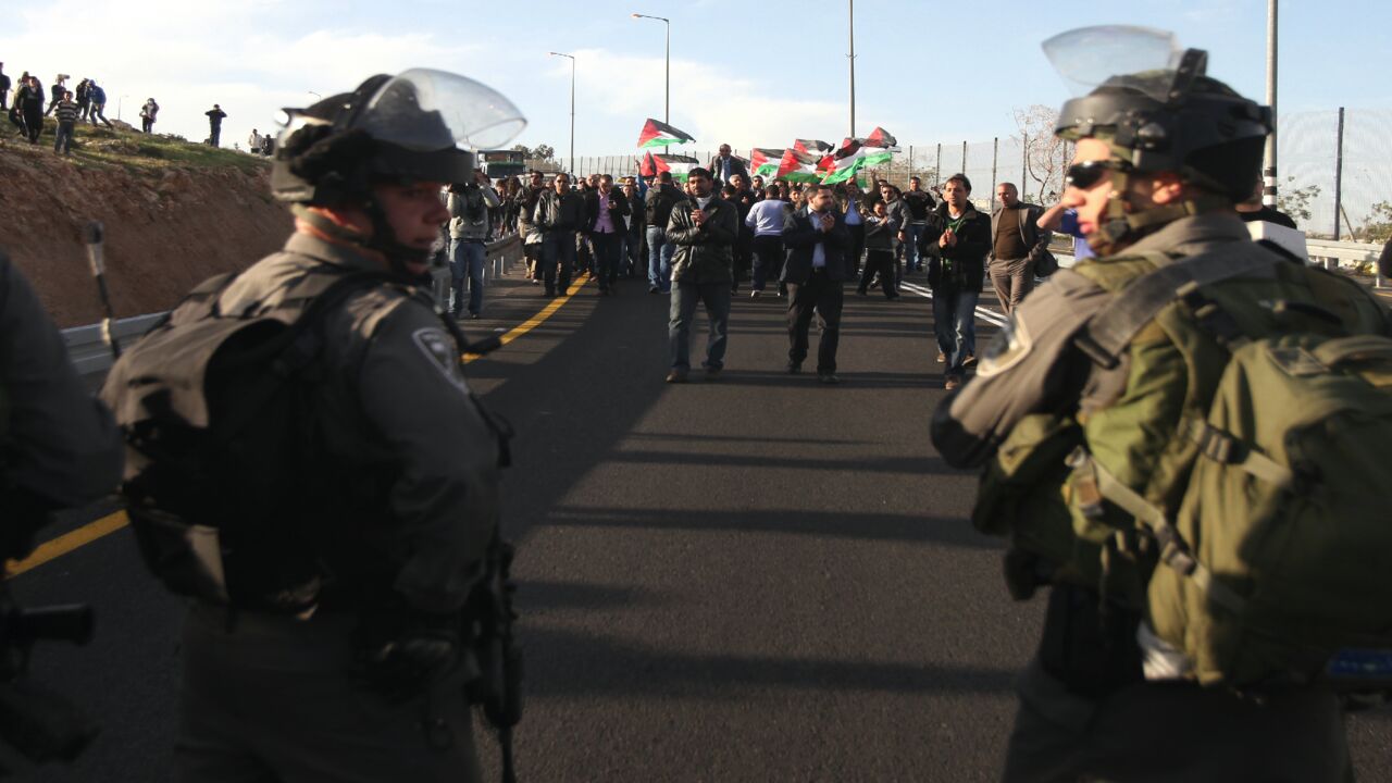 Israeli soldiers stand ready to prevent the progress of a symbolic wedding party toward the Israeli-constructed controversial separation barrier close to the Israeli-manned checkpoint of Hezma in the Israeli-occupied West Bank, between Jerusalem and the Palestinian city of Ramallah on March 9, 2013. 