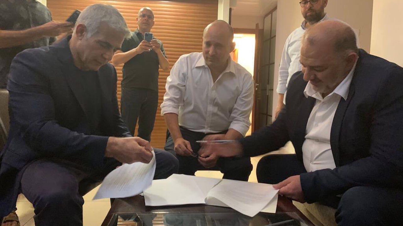 Ra'am Party leader Mansour Abbas (L) signs a coalition agreement with Yair Lapid (L) and Naftali Bennett (C) in Jerusalem, June 2, 2021.