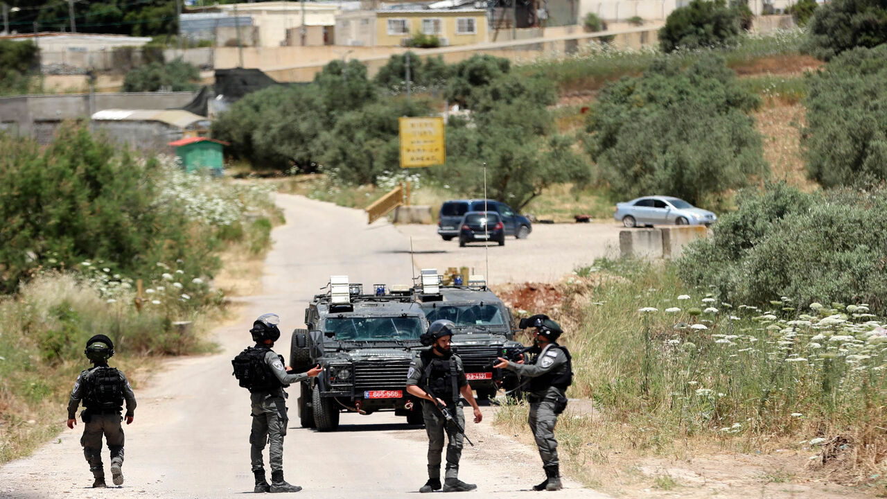 Members of the Israeli security block the road near the Salem checkpoint leading to Jenin, following an attack by Palestinians on an Israeli base, pictured in the background, West Bank, May 7, 2021.