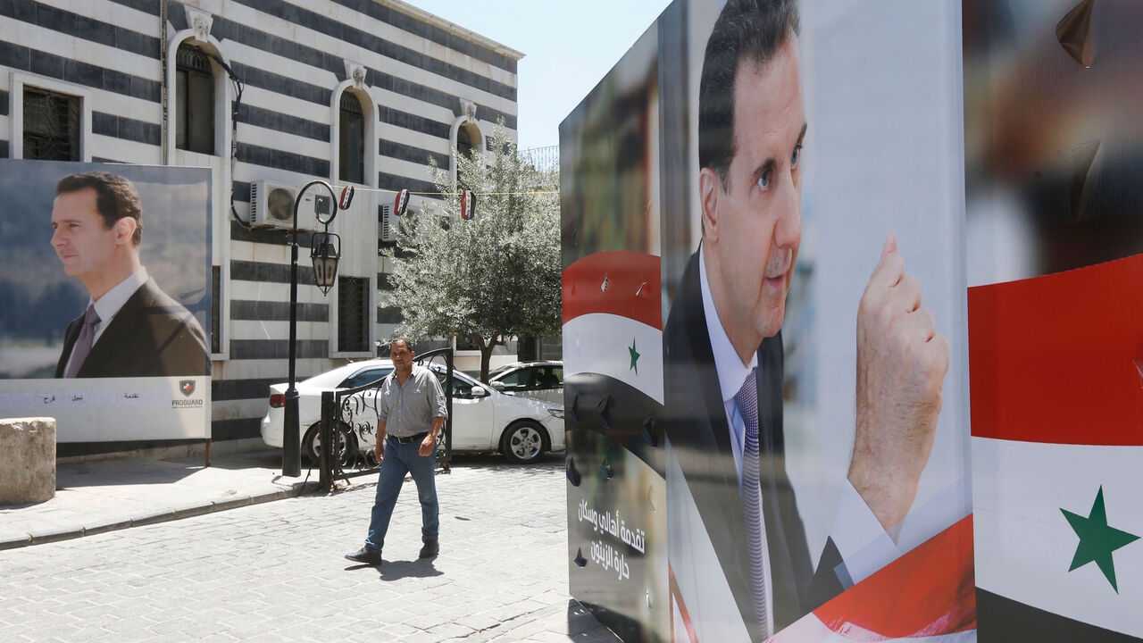 A Syrian man walks walks in between election campaign posters bearing portraits of Syrian President Bashar al-Assad, a candidate for the upcoming presidential election, in the capital Damascus on May 18, 2021.