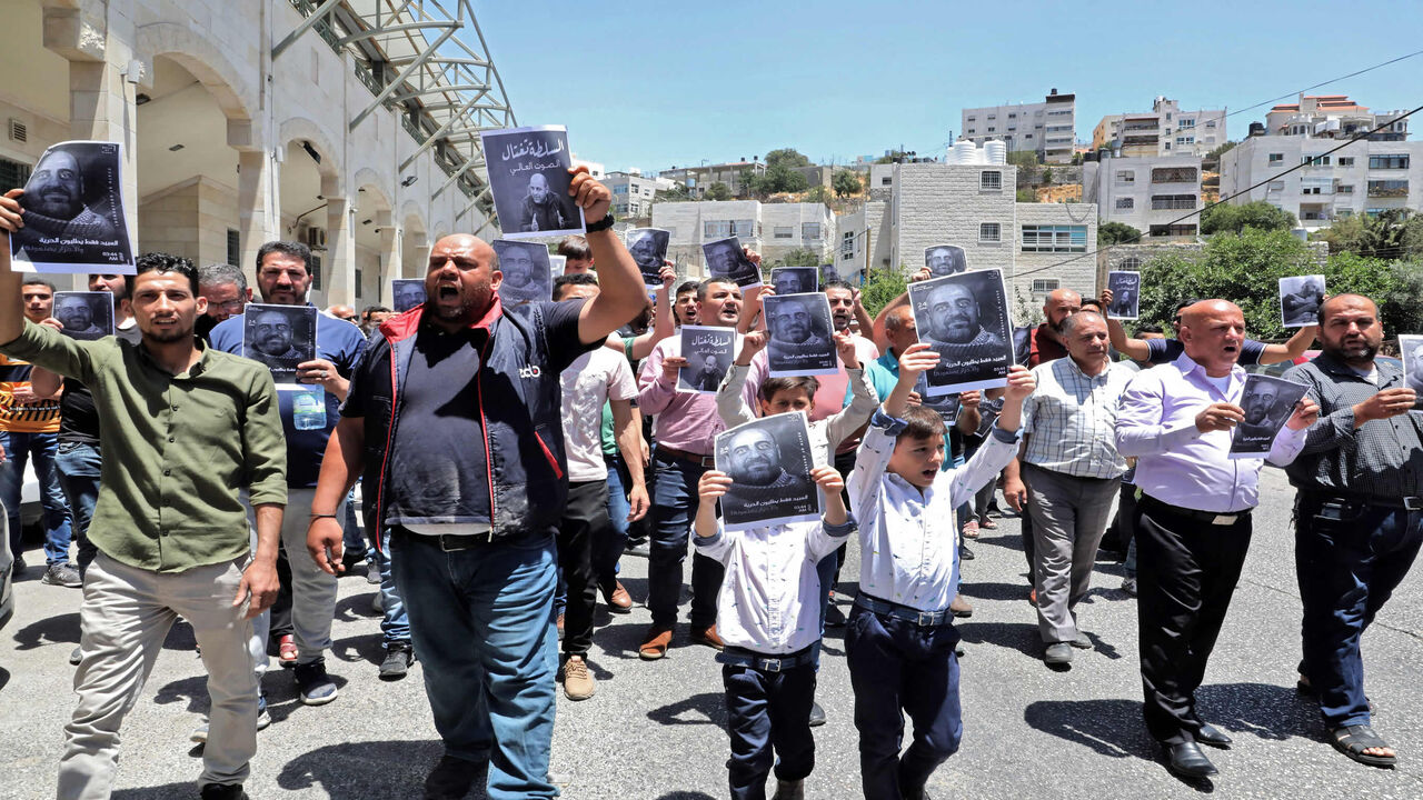 Demonstrators hold up images of Palestinian activist Nizar Banat, who died in late June during a violent arrest by Palestinian Authority security forces, as they march during a protest in the city of Hebron, West Bank, July 2, 2021.