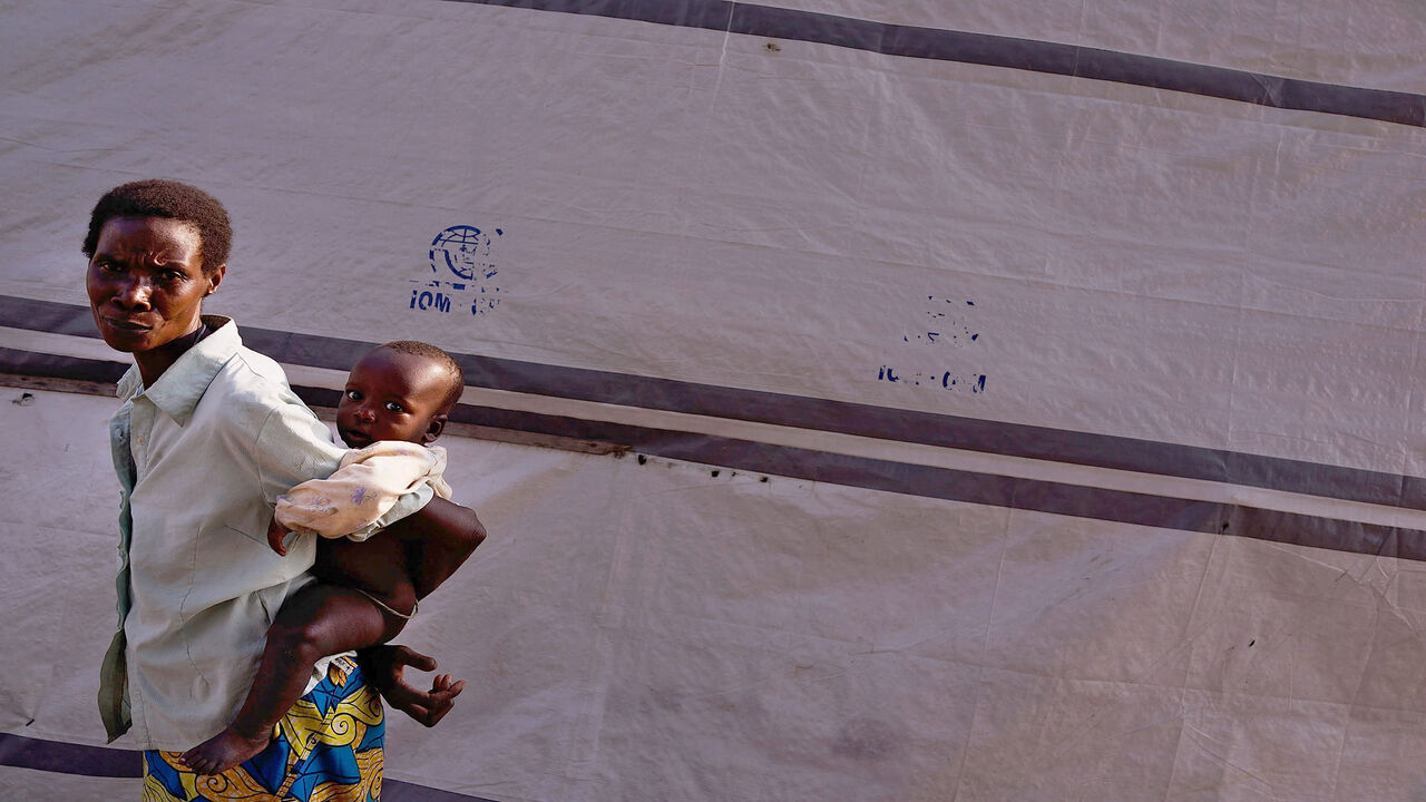 A woman pauses with her child in a camp for people displaced in conflicts and turmoil that has afflicted Burundi over the last 25 years, Carama, Burundi, June 23, 2015.