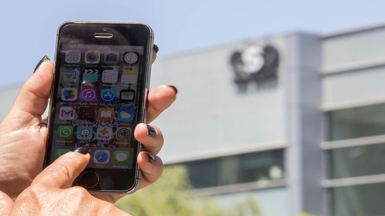 An Israeli woman uses her iPhone in front of the building housing the Israeli NSO group, Herzliya, Israel, Aug. 28, 2016.