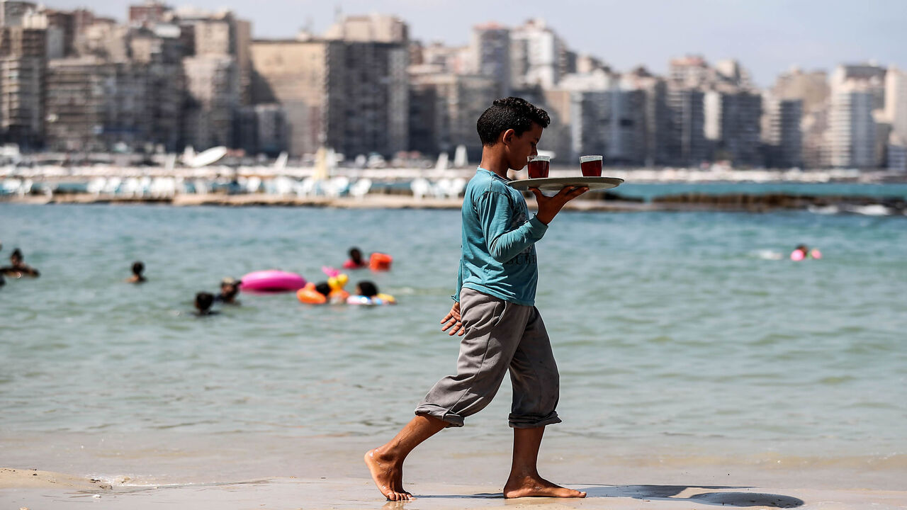 An Egyptian tea street vendor walks on a beach, Alexandria, Egypt, Aug. 01, 2019.