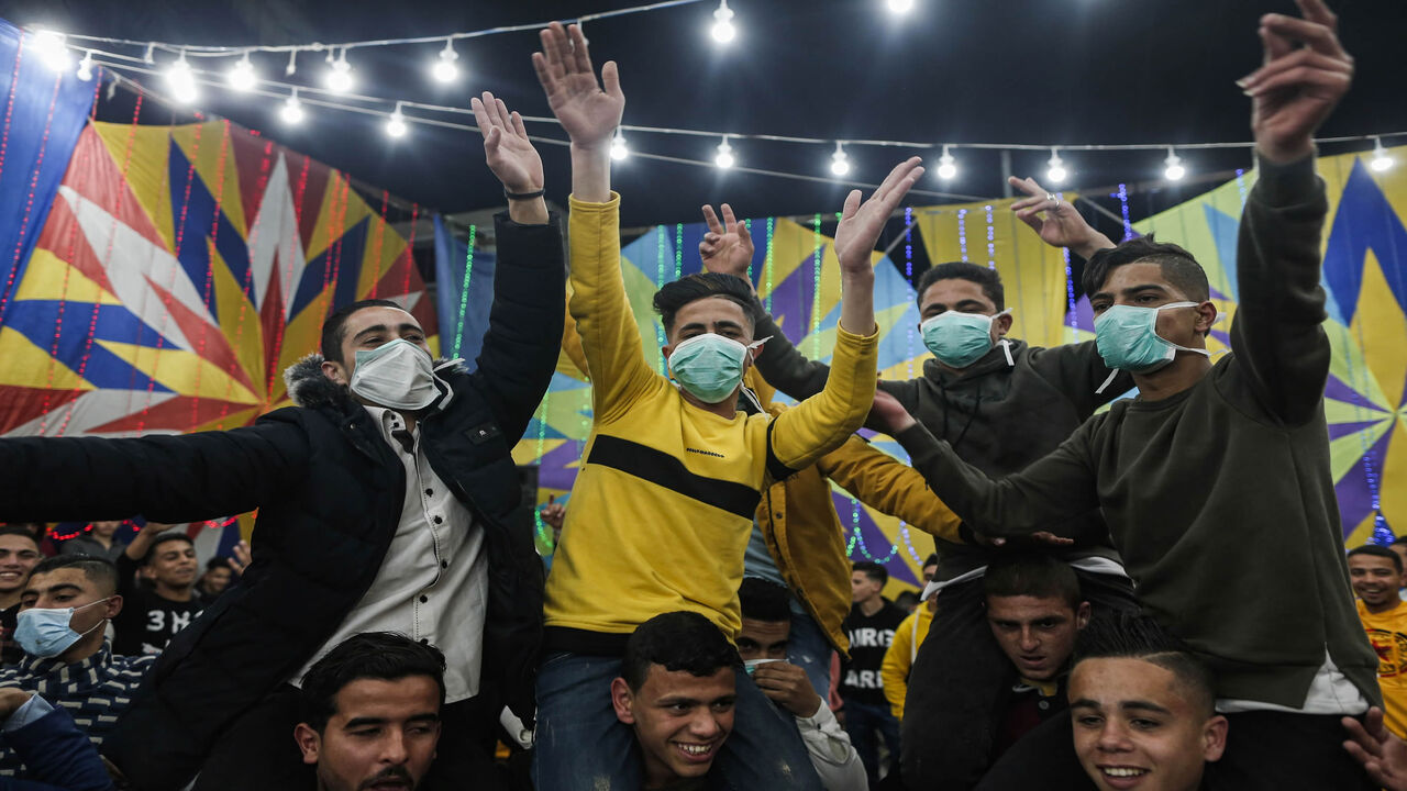 Palestinian men, some wearing face masks, dance at a wedding a day before authorities impose a ban on festive events as a protective measure against the coronavirus pandemic, Rafah, Gaza Strip, March 21, 2020.