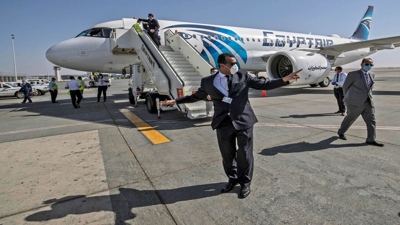 Egyptian officials wearing face masks against the coronavirus are pictured near an EgyptAir Airbus A320 neo aircraft at Hurghada Airport, Egypt, June 18, 2020.