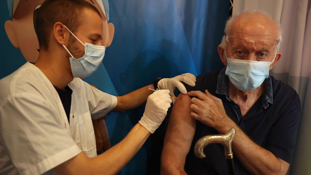 An Israeli medic anministers a dose of the Pfizer-BioNTech vaccine against the coronavirus to a man, at a Clalit Health Services station set up inside Cinema City complex in Jerusalem, on Aug. 11, 2021.