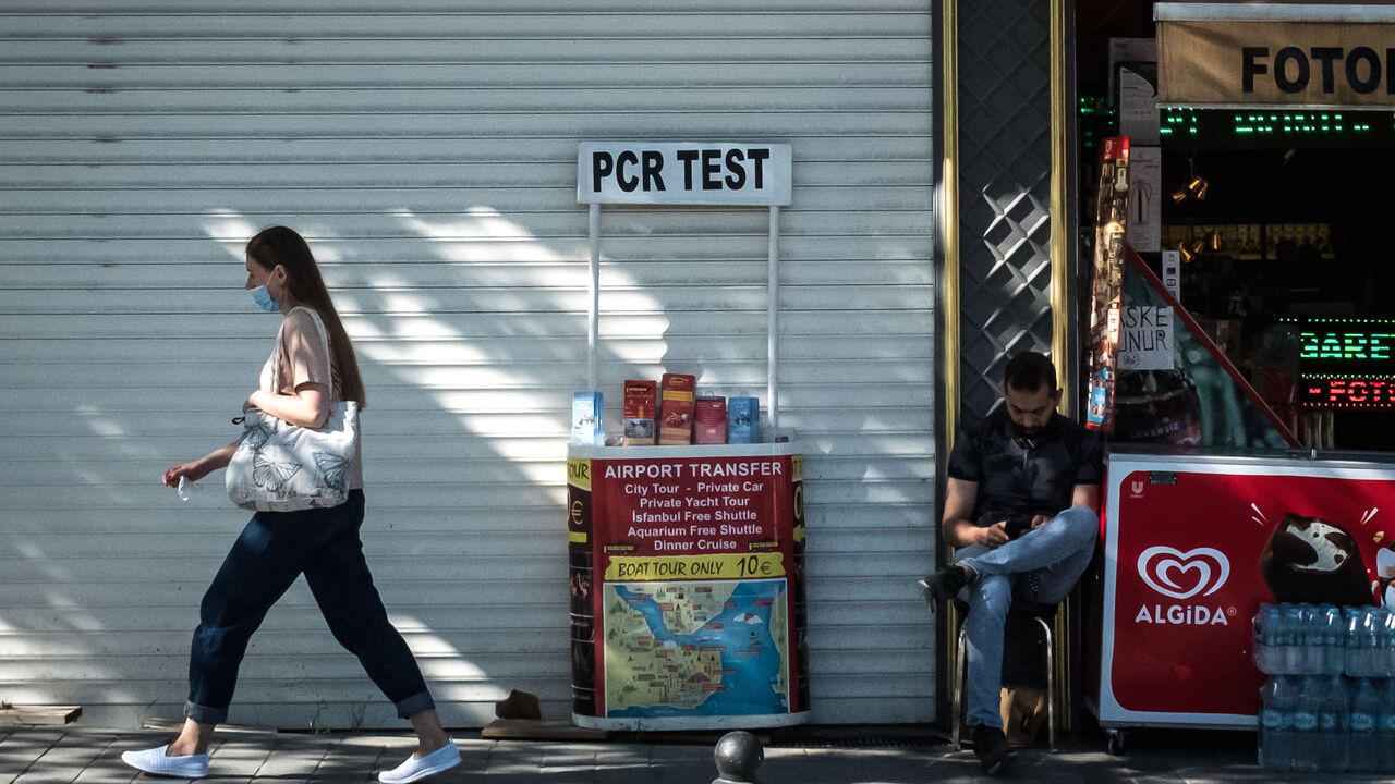 A woman walks past a tourist shop promoting PCR tests during a three week nationwide coronavirus lockdown on May 5, 2021 in Istanbul, Turkey. 