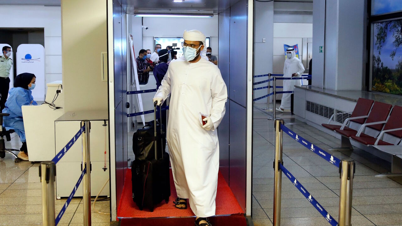 An incoming passenger crosses with his luggage through a disinfection tunnel upon arriving on an Emirates flight at the Iranian capital Tehran's Imam Khomeini International Airport on July 17, 2020.
