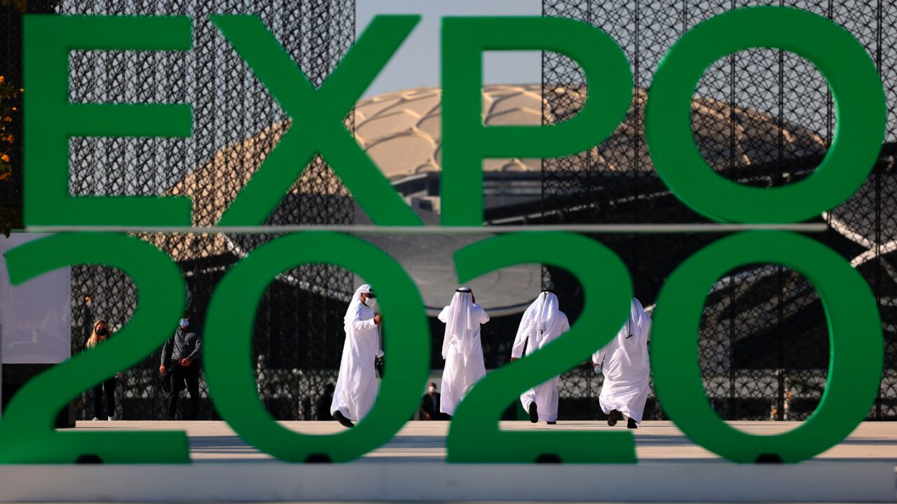 People walk behind the official sign marking the Dubai Expo 2020 near the Sustainability Pavilion in Dubai on Jan. 16, 2021.