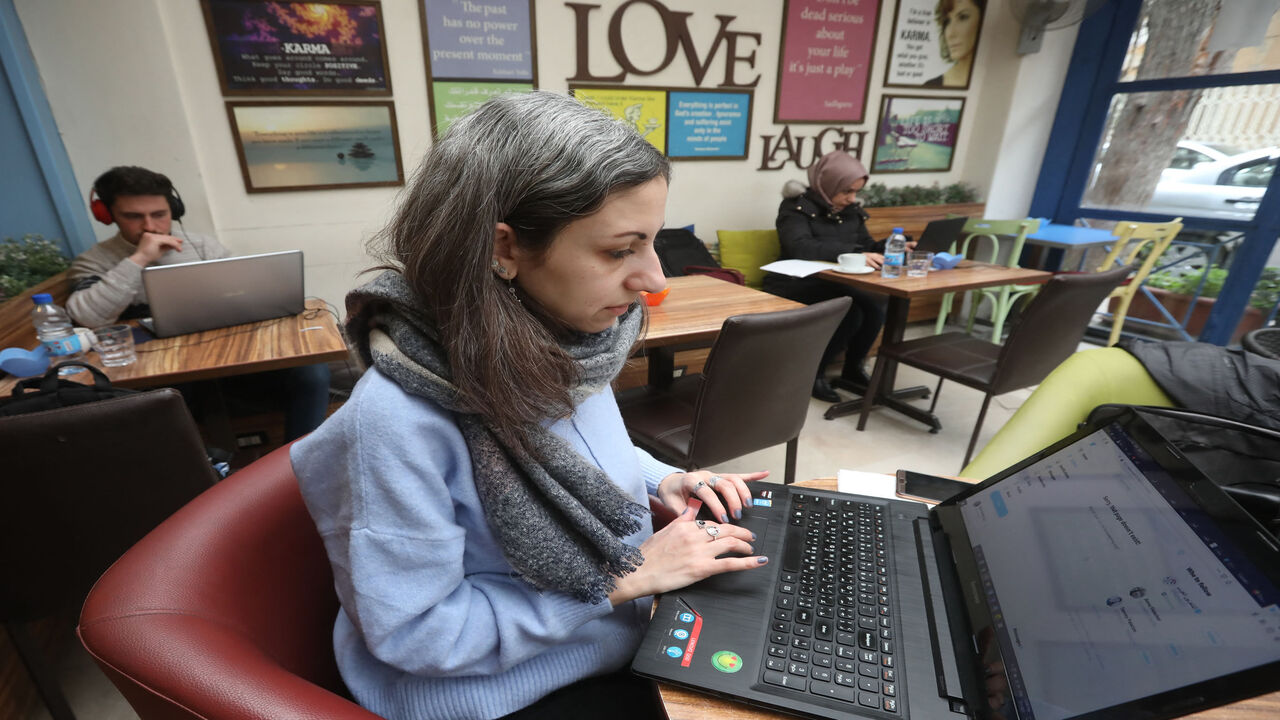 Syrian journalist Zeina Shahla types on her laptop at a cafe, Damascus, Syria, March 1, 2021.