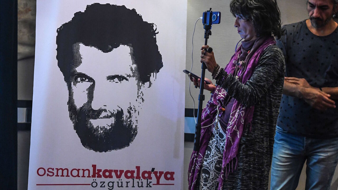 A journalist stands in front of a poster featuring jailed businessman and philanthropist Osman Kavala during a press conference of his lawyers on Oct. 31, 2018.