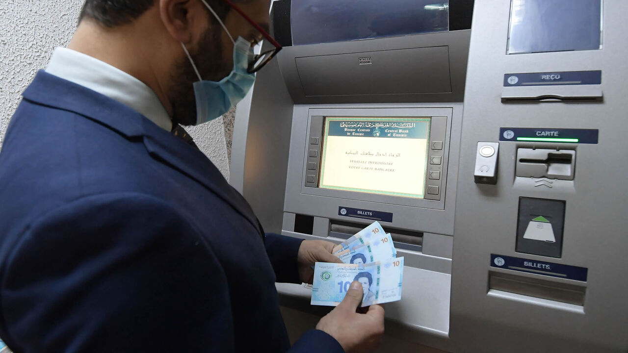 A man retrieves newly circulating Tunisian bank notes from an ATM, Tunis, Tunisia, March 27, 2020.