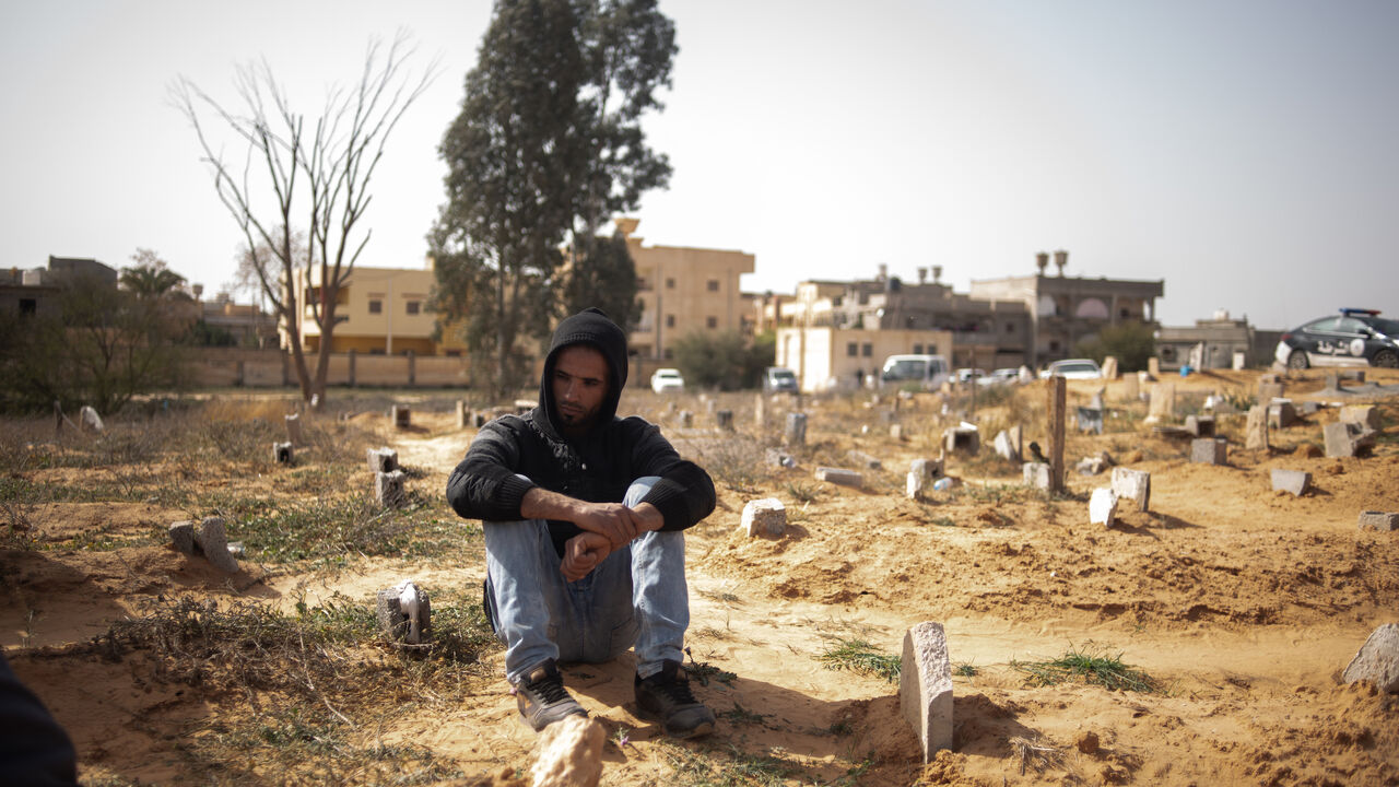 A family member grieves next to the grave of his brother, Moaid Amer, who is amongst victims of Al-Kaneyat massacres, during burial in the cemetery of Tarhuna on March 5, 2021 in Tarhuna, Libya.