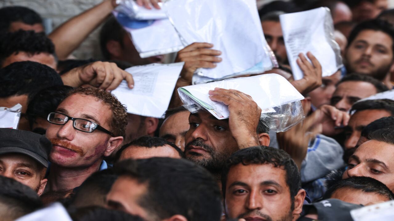 Palestinian men gather to apply for work permits in Israel, at Jabalia refugee camp in the northern Gaza Strip, on Oct. 6, 2021.