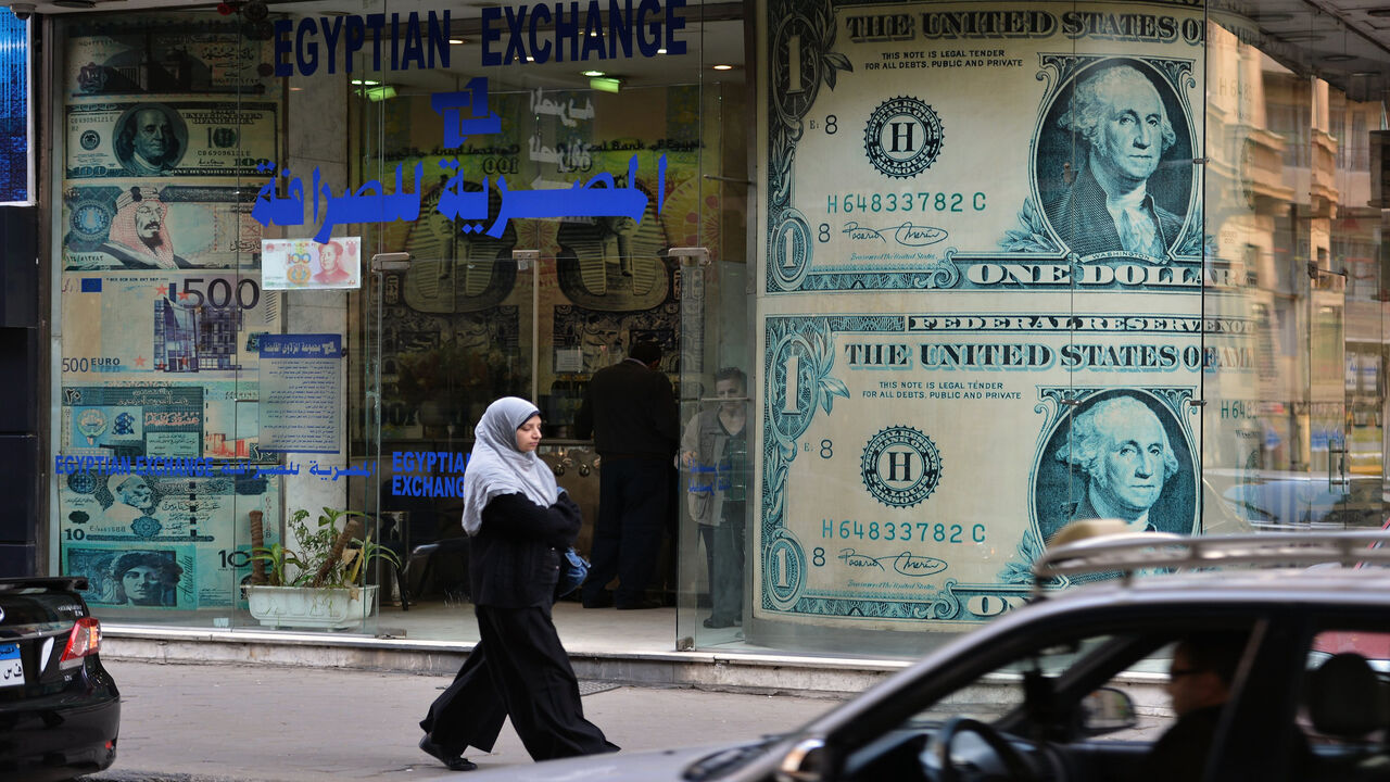 A woman walks past an exchange store, Cairo, Egypt, Jan. 6, 2013.