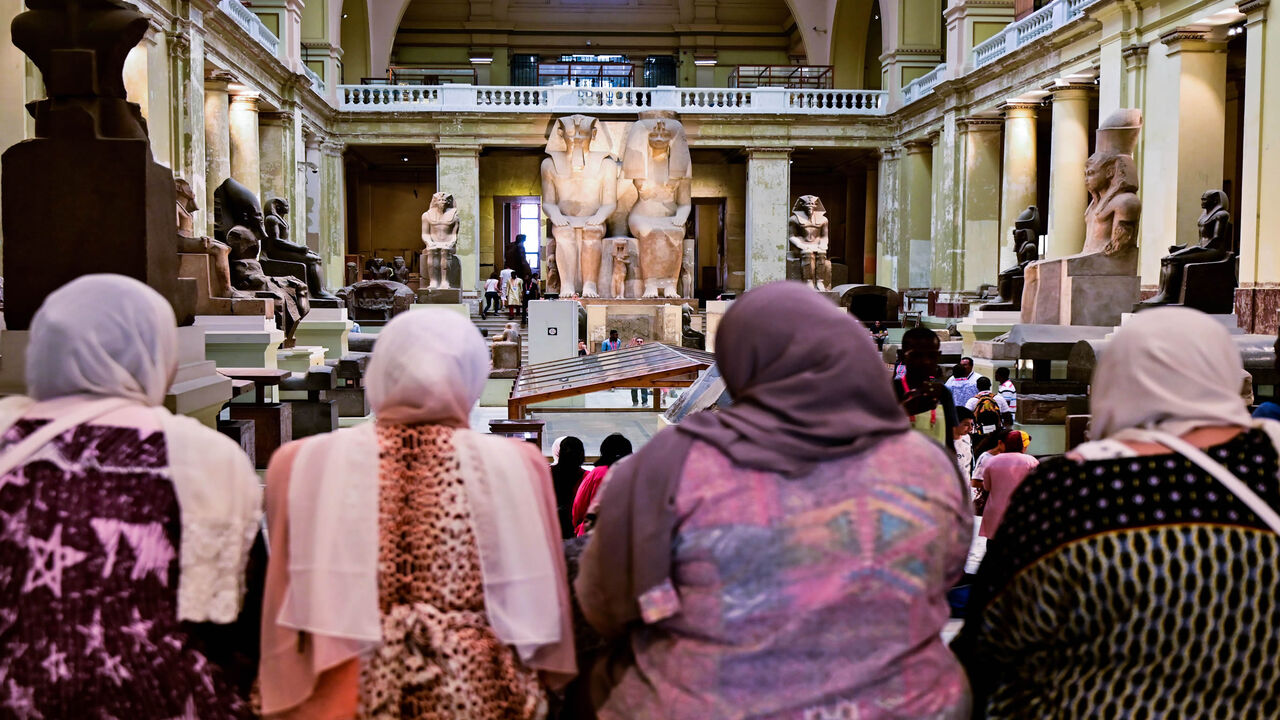 A group of women sit in front of the Colossal statue of Amenhotep III and Tiye at the Cairo Museum, Cairo, Egypt, July 15, 2019.