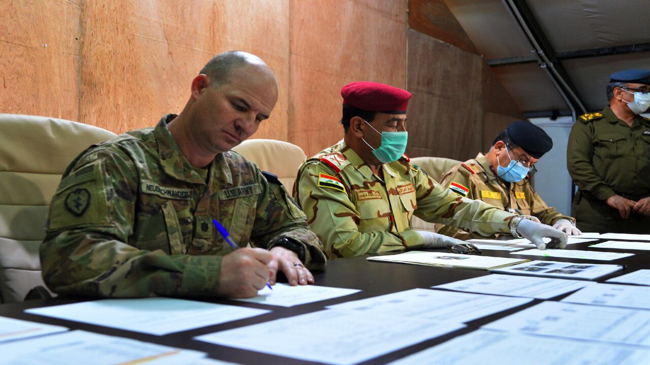 US Army Cmdr. Jace Neuenschwander (L) and Iraq Nineveh Operations Cmdr. Maj. Gen. Noman Zawbai (C) and Iraq's Staff Maj. Gen. Mohammad Fadhel Abbas sign documents.