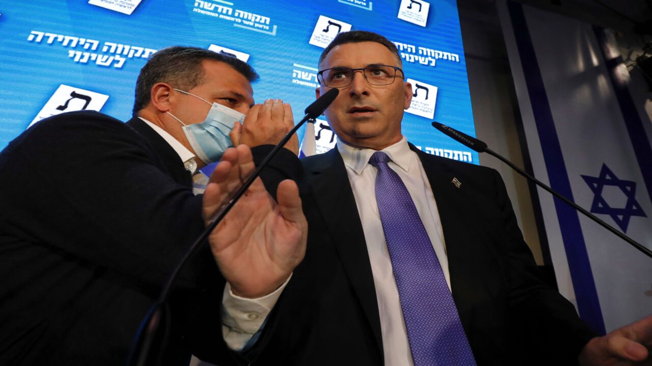 An aide whispers to Gideon Saar (R), leader of Israel's Tikva Hadasha (New Hope) party, as he addresses supporters at his party's campaign headquarters.