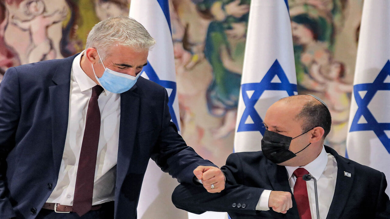 Israeli Prime Minister Naftali Bennett (R) elbow-bumps Alternate Prime Minister and Foreign Minister Yair Lapid before the start of the weekly Cabinet meeting in the Knesset building, Jerusalem, July 19, 2021.