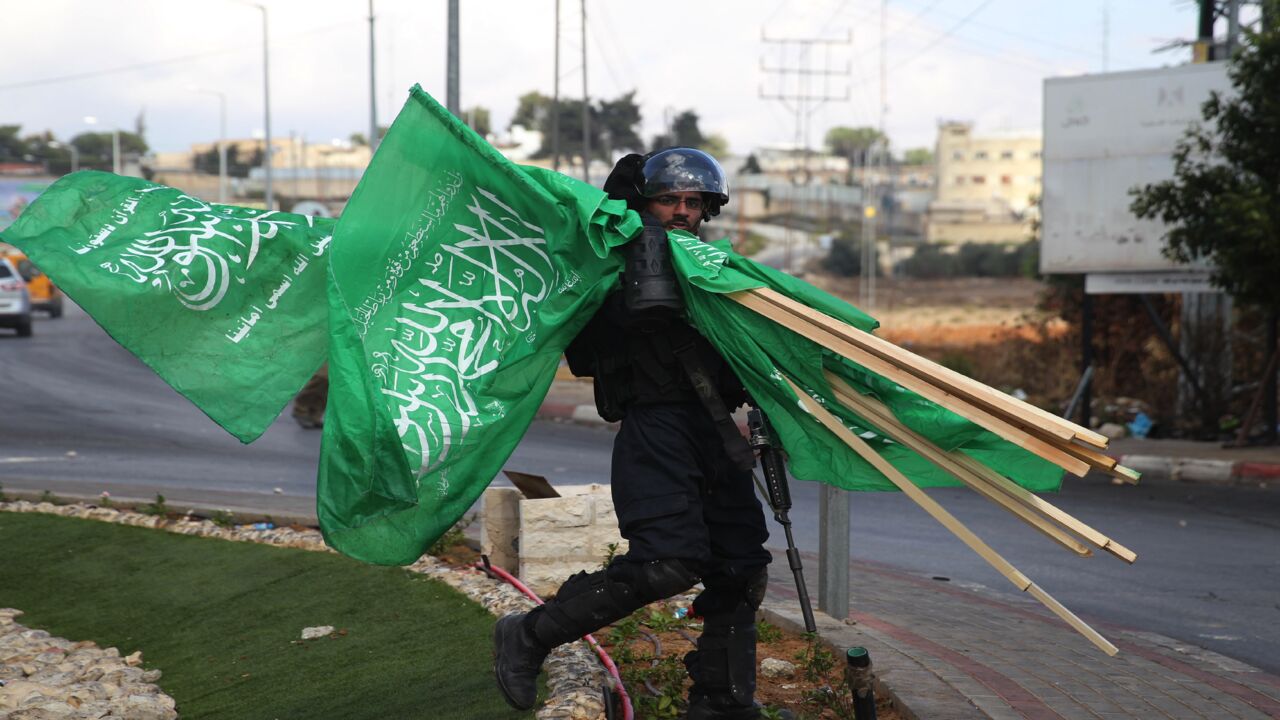 A member of Israel's security forces carries flags of Hamas that were seized during clashes with Palestinian protesters north of Ramallah in the West Bank, on Oct. 8, 2015.