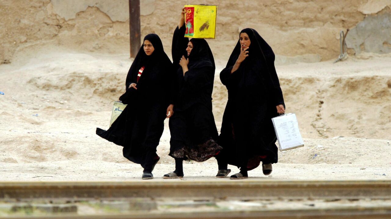 Women carry goods down train tracks in the village of Shaibah, near Basra in southern Iraq, April 10, 2003.