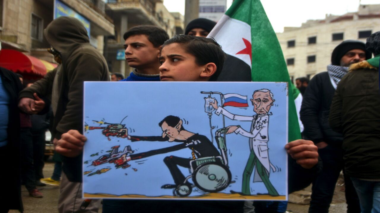 A Syrian holds a caricature of Bashar al-Assad and Vladimir Putin in a demonstration against the continuing assault by the Syrian regime and Russian forces in Idlib on Feb. 21, 2020.