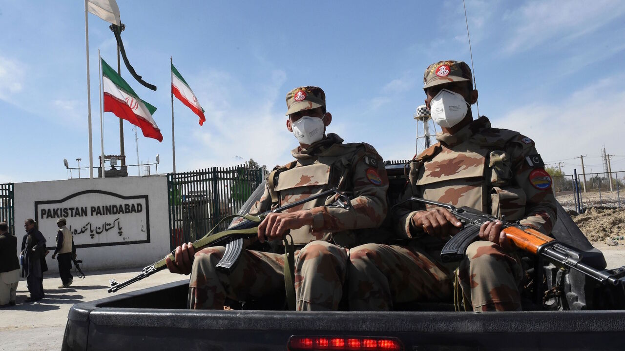 Pakistani soldiers wearing facemasks patrol near the closed Pakistan-Iran border in Taftan on Feb. 25, 2020 as fears over the spread of the COVID-19 coronavirus escalate following an outbreak in neighboring Iran. 